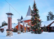 Verschneites Dorf mit Weihnachtsbaum und Holzhäusern.