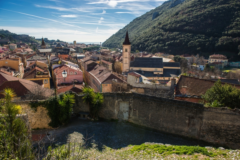 Italienische Kleinstadt mit Kirche und Hügel im Hintergrund.