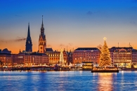 Abendliche Skyline von Hamburg mit Weihnachtsbaum und Lichtern am Wasser.