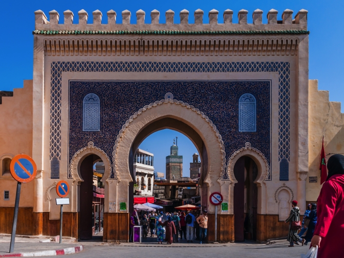 Blaue Tor in Fes, Marokko, mit Menschen und Markt im Hintergrund.