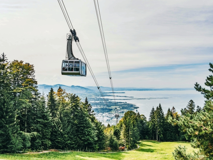 Seilbahn über grünen Hügeln mit See im Hintergrund