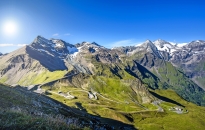 Serpentinenschleifen einer Straße im alpinen Hochgebirge mit schneebedeckten Gipfeln.