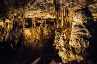 Stalagmiten und Stalaktiten in einer beleuchteten Höhle.