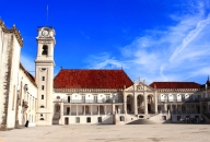 Historisches Gebäude mit Uhrturm und rotem Dach unter blauem Himmel.