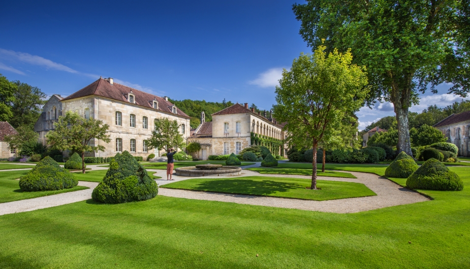 Historisches Gebäude mit gepflegtem Garten und Rundwegen bei sonnigem Wetter.