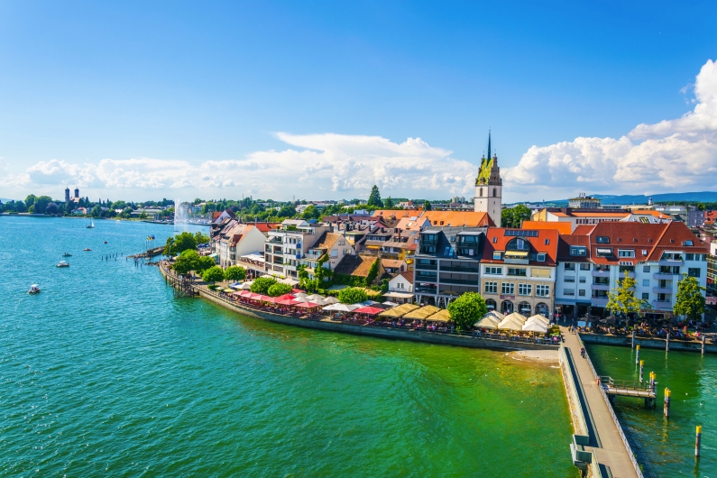 Blick auf eine Stadt am Bodensee mit Hafen und historischen Gebäuden.