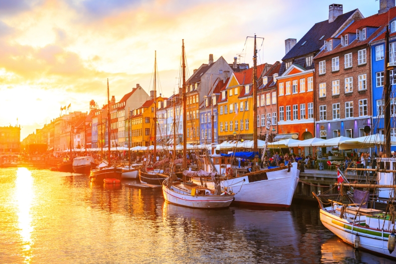 Hafenansicht mit farbenfrohen Gebäuden und Segelbooten bei Sonnenuntergang in Nyhavn, Kopenhagen.