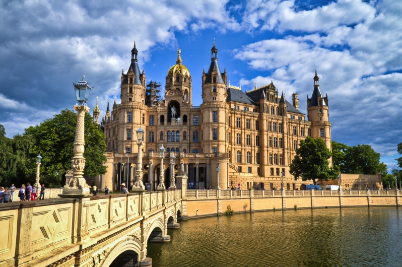 Schloss mit Türmen und Brücke unter blauem Himmel.