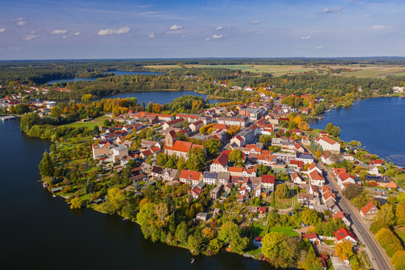 Luftaufnahme einer kleinen Stadt am Seeufer mit umliegender Landschaft.