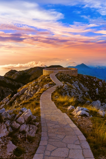 Steinweg führt zu einem Aussichtspunkt auf einem Berg bei Sonnenuntergang.