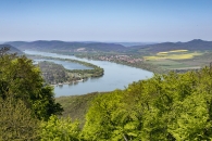 Landschaft mit Fluss und bewaldeten Hügeln unter blauem Himmel.