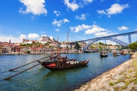Boote auf einem Fluss vor einer Brücke in einer Stadtlandschaft mit blauem Himmel.