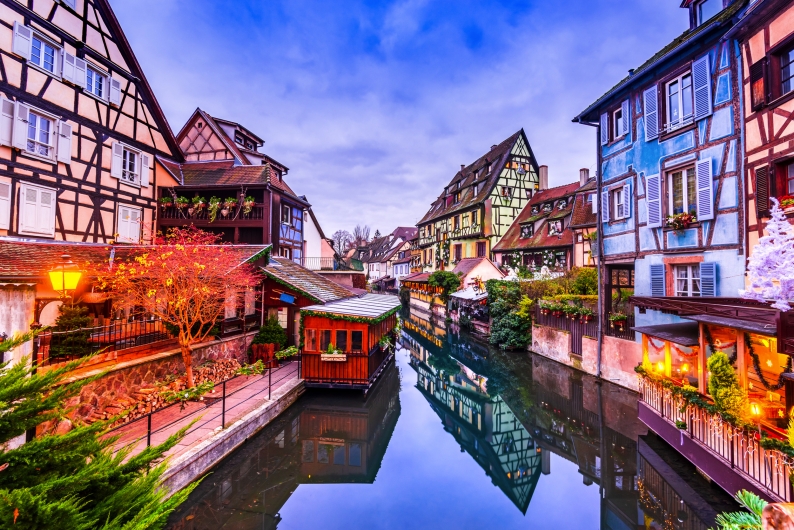 Fachwerkhäuser und Kanal in einer malerischen Stadt bei Dämmerung.