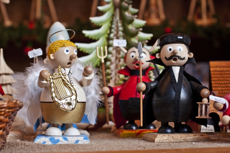 Holzfiguren von Engeln und Figuren in Weihnachtskostümen auf einem Markt.
