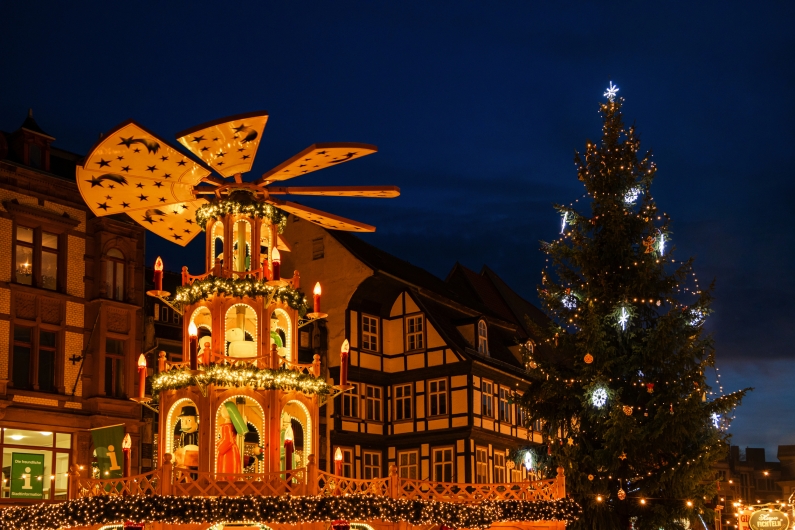 Weihnachtspyramide und beleuchteter Baum vor Fachwerkhaus im Abendlicht