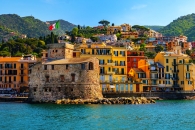 Festung und bunte Häuser am Meer mit Bergen im Hintergrund