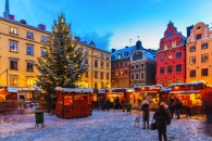 Weihnachtsmarkt auf einem verschneiten Platz mit geschmücktem Tannenbaum in der Abenddämmerung