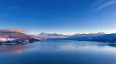 Panoramablick auf einen See in einer winterlichen Berglandschaft bei klarem Himmel.