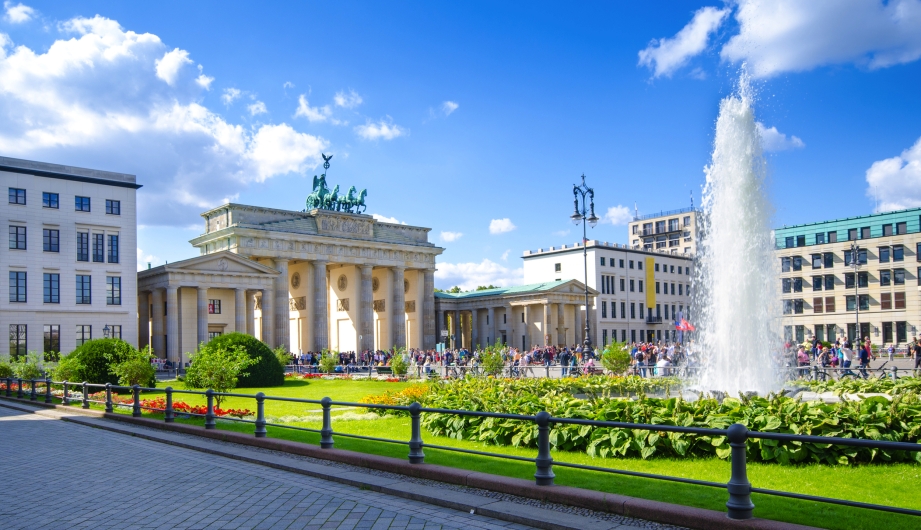 Brandenburger Tor in Berlin mit Springbrunnen und blauen Himmel.