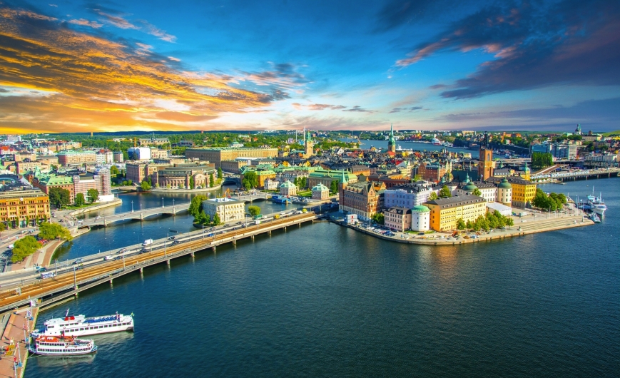 Panoramablick auf eine Stadt mit Flüssen und Brücken bei Sonnenuntergang.