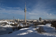 Olympiaturm im verschneiten Olympiapark, München, bei klarem Himmel.