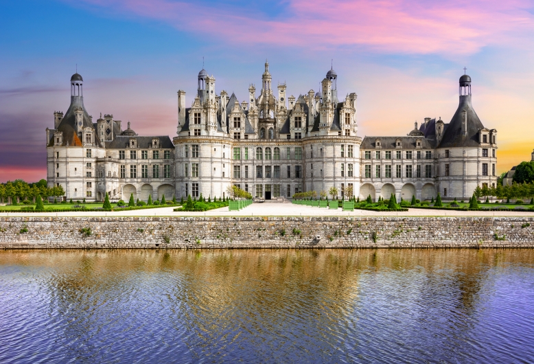 Schloss Chambord an einem ruhigen Fluss bei Sonnenuntergang.