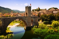 Steinbrücke und historische Stadt mit Fluss und Hügeln im Hintergrund.