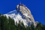 Schneebedeckter Berg mit Gebäude auf dem Gipfel, blauer Himmel.
