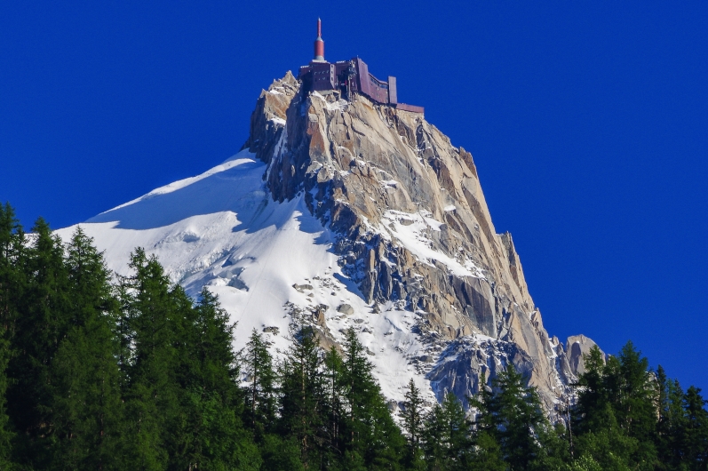Schneebedeckter Berg mit Gebäude auf dem Gipfel, blauer Himmel.