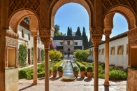 Mittelalterlicher Hof mit Arkaden und Springbrunnen im Garten.
