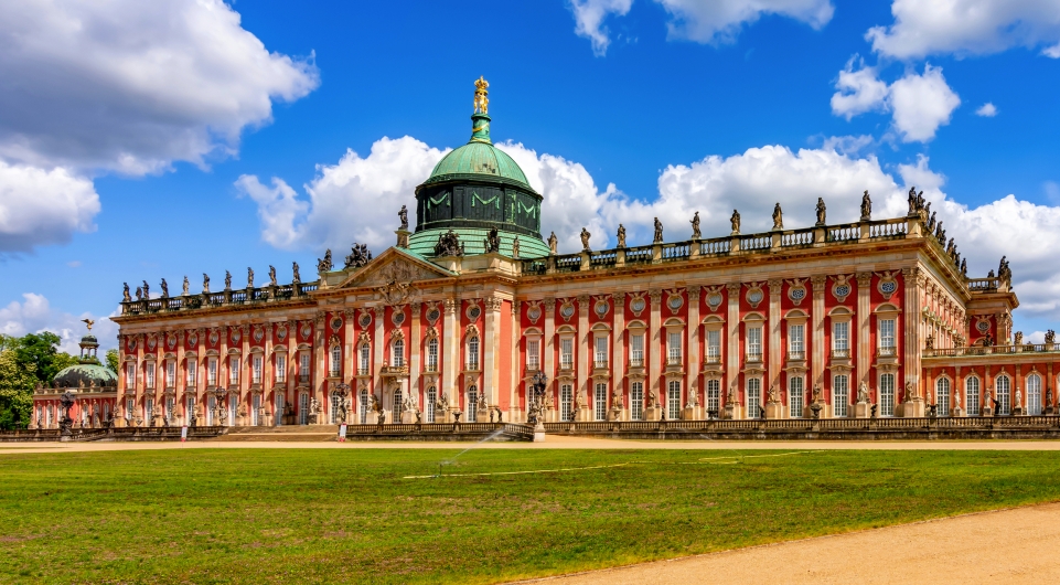 Historisches Schloss mit Kuppel vor blauem Himmel.