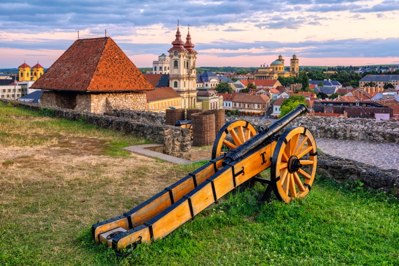 Alte Kanone auf einer Festung mit Stadtblick im Hintergrund bei Sonnenuntergang