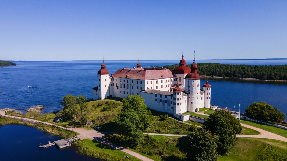 Schloss am See mit Türmen und Bäumen im Sommer.