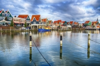 Hafen mit bunten Häusern und Boot, unter bewölktem Himmel.