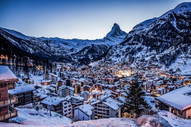 Verschneite Berglandschaft mit Dorf im Abendlicht, Matterhorn im Hintergrund.
