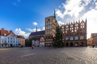Marktplatz mit historischem Gebäude und Weihnachtsbaum bei klarem Himmel.