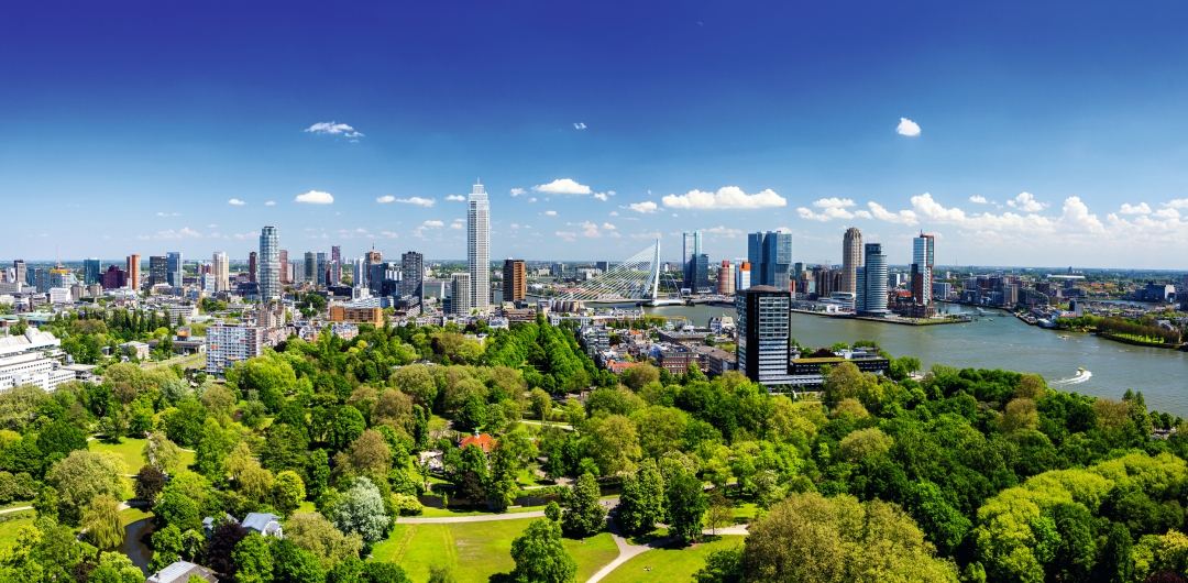 Panorama einer Stadt mit modernen Hochhäusern und einem Fluss im Vordergrund.