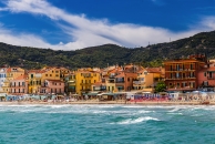 Bunte Häuser und Strand vor grünen Hügeln an der Küste