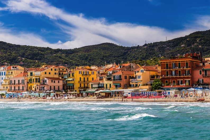 Bunte Häuser und Strand vor grünen Hügeln an der Küste