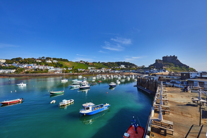 Boote im Hafen mit Burg im Hintergrund bei blauem Himmel