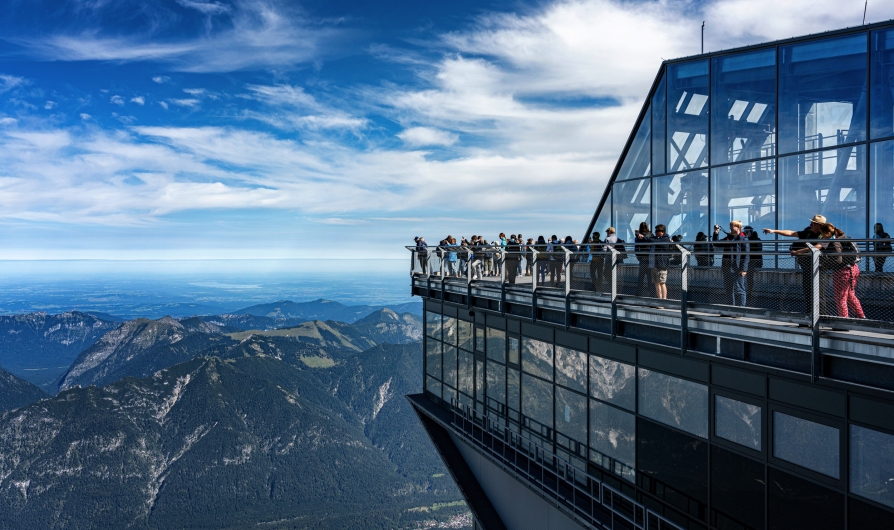 Menschen auf einer Aussichtsplattform in den Bergen mit weiten Blicken in die Landschaft.