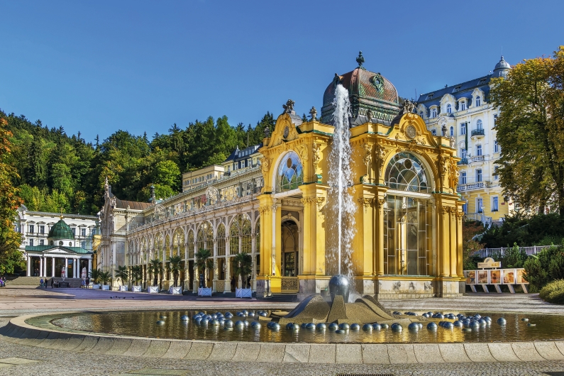 Kurhausgebäude mit Springbrunnen im Vordergrund und blauem Himmel im Hintergrund.