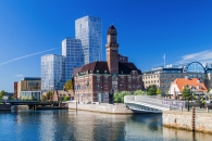 Stadtszene mit historischem Gebäude und modernen Wolkenkratzern an einem Fluss.