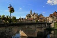 Steinbrücke mit Blumen und Gebäude in Périgueux, blauer Himmel im Hintergrund.