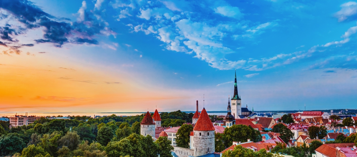 Blick auf eine mittelalterliche Stadt mit Türmen und farbenfrohem Sonnenuntergang.