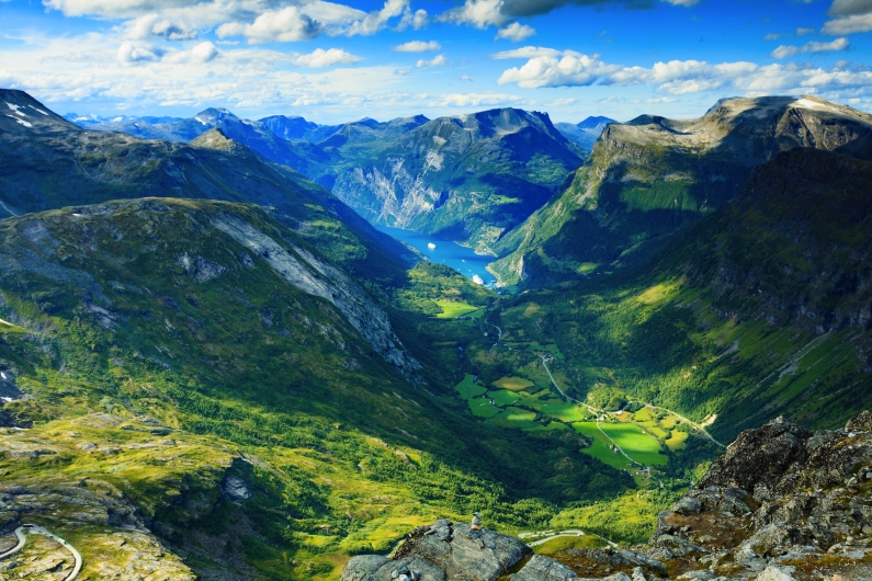 Blick auf grüne Norwegische Fjordlandschaft mit Bergen und blauem Himmel.