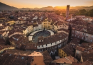 Luftaufnahme einer Piazza in italienischer Stadt bei Sonnenuntergang mit umliegenden Dächern.