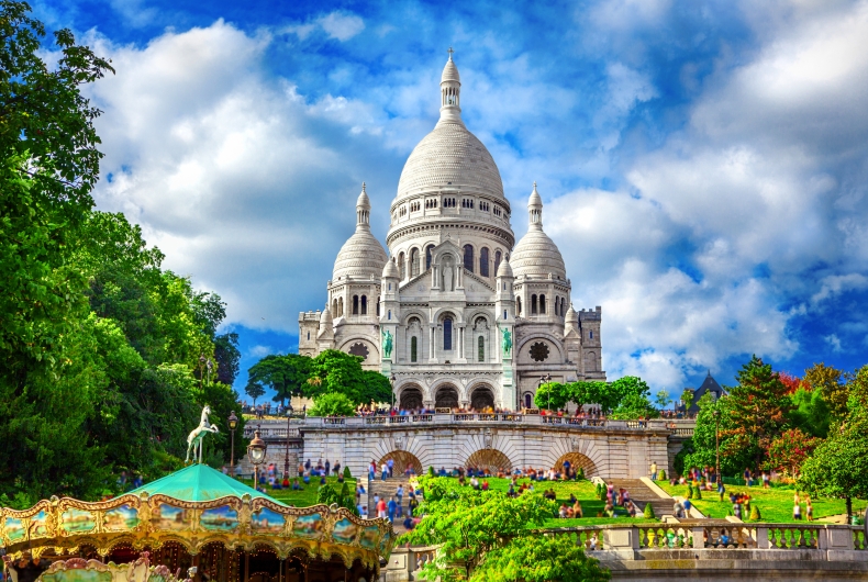Blick auf die Basilika Sacré-Cœur in Paris, mit Karussell im Vordergrund.