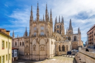 Gotische Kathedrale mit spitzen Türmen bei Tageslicht, umgeben von Gebäuden.