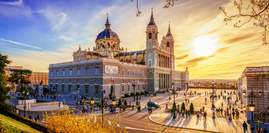 Kathedrale Almudena in Madrid bei Sonnenuntergang, mit Menschen auf dem Platz davor.
